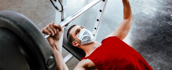 homem branco com máscara fazendo exercício de musculação